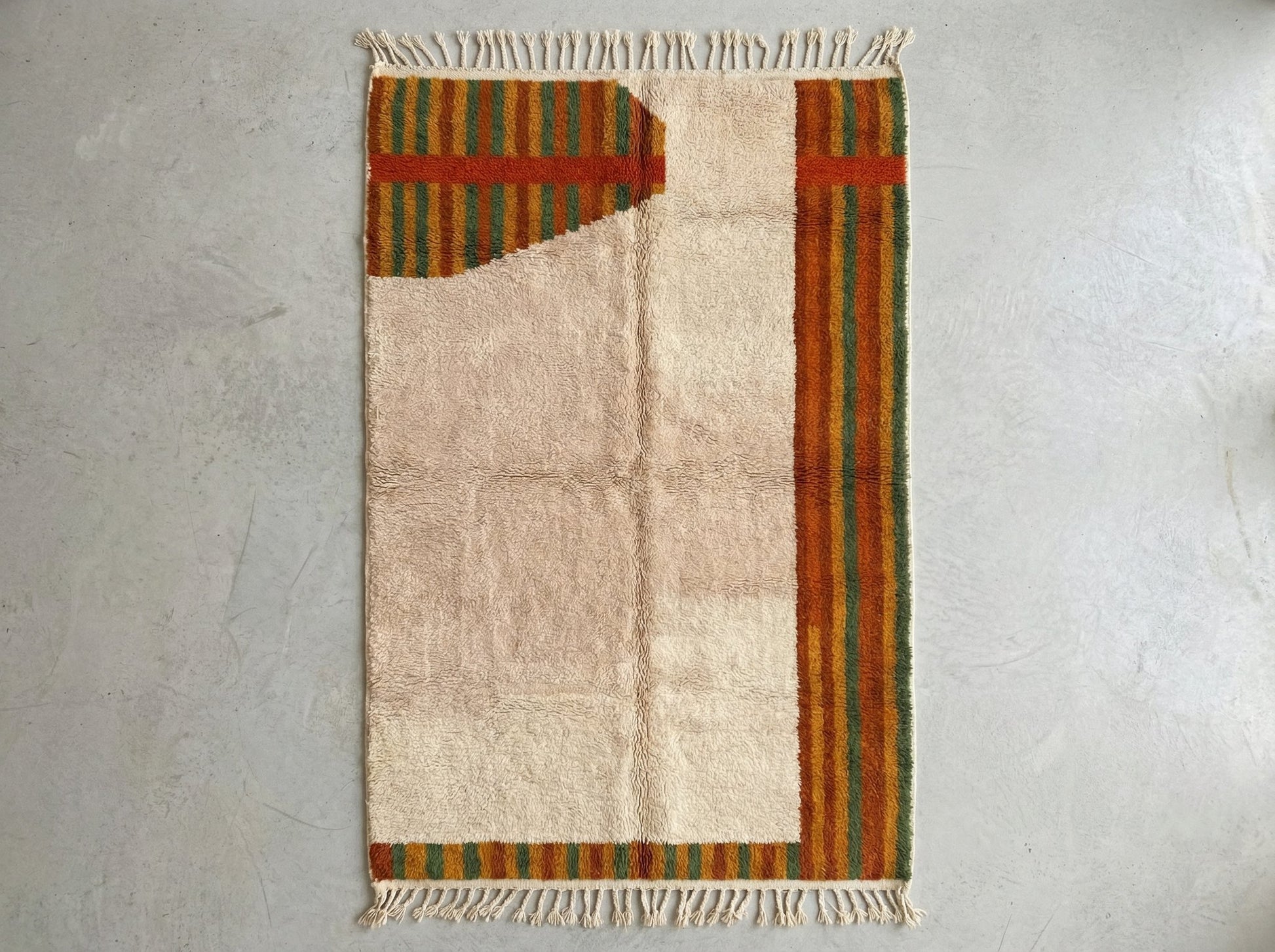 Custom made Beni Ourain Moroccan wool rug featuring geometric diamond patterns in rust, marmalade, pesto green, and classic beige tones with traditional fringe.