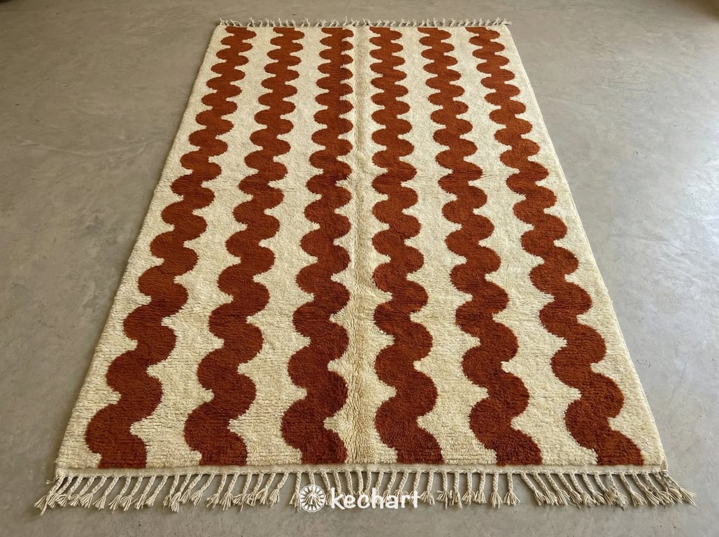 Custom made Beni Ourain Moroccan wool rug in natural cream with rust geometric diamond pattern and traditional fringe. Plush, shaggy texture handwoven by artisans in the Atlas Mountains.