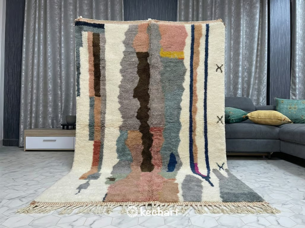 Close up view of the thick, hand-knotted wool pile of a Beni Ourain rug, highlighting natural fiber variations in taupe, sand, and cool grey tones.
