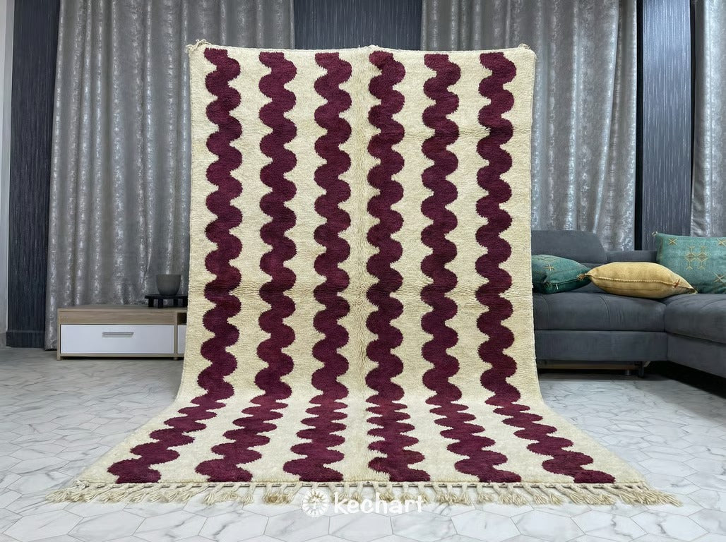 Large custom Moroccan wool area rug with cream and Bordeaux diamond design anchoring a contemporary living room with a neutral linen sofa and wood coffee table.