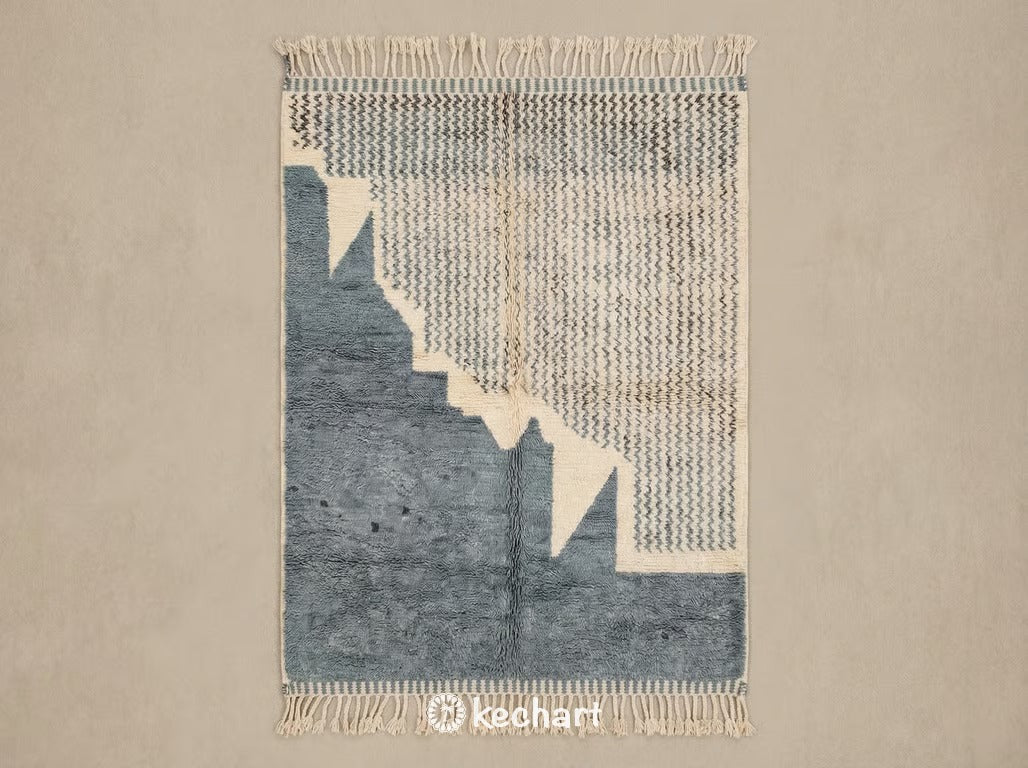 Custom made to order Beni Ourain Moroccan rug flat lay showing plush cream wool pile with medium density geometric diamond pattern in charcoal and dusty blue grey accents with traditional fringe.
