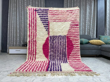 Large custom Moroccan area rug in a modern bohemian living room anchoring a white linen sofa and wooden coffee table