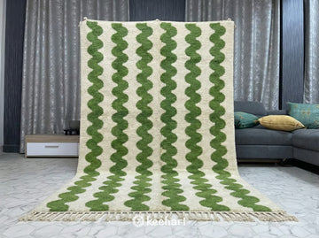 Plush shaggy Beni Ourain rug placed under a large bed in a serene, neutral master bedroom, adding texture and a pop of green color.