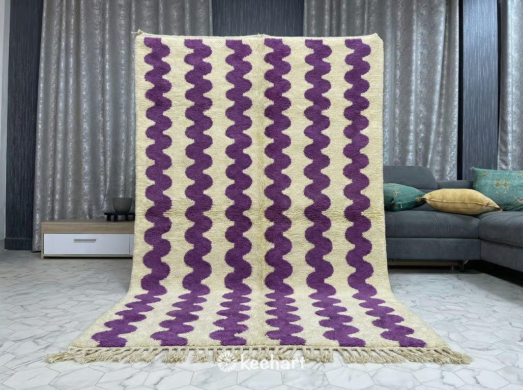 Large Beni Ourain shag rug placed under a bed in a serene master bedroom, adding texture and pops of orchid color to a minimalist design scheme.