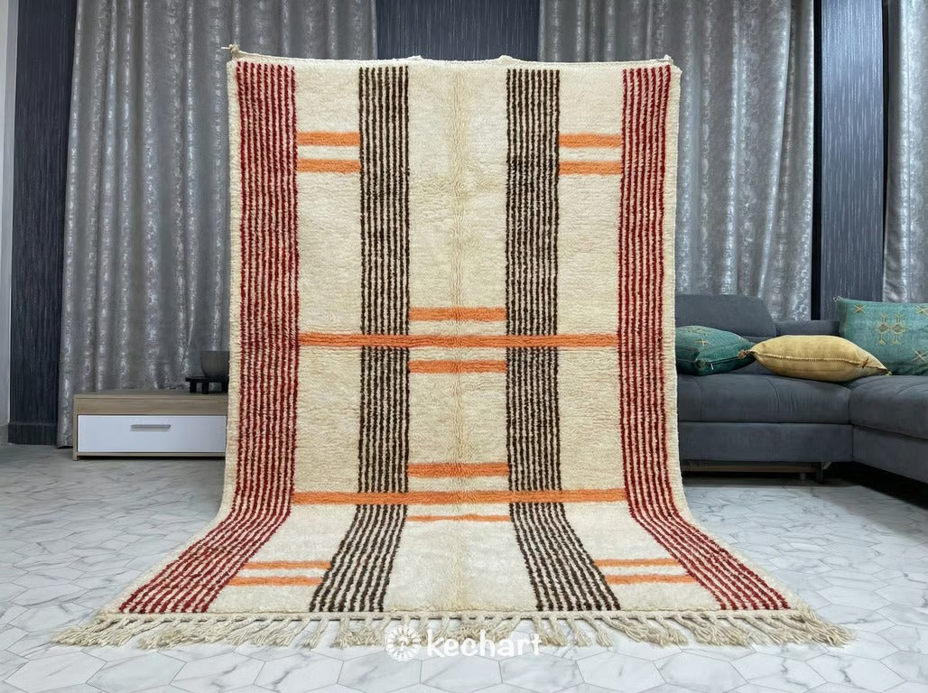 Close-up detail shot of the handwoven Beni Ourain wool pile, showing the rich texture and intricate interplay of crimson, orange, and chocolate yarns in the diamond pattern.
