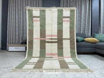 Close-up detail of the hand-knotted wool texture, traditional fringe, and the sage green and pink diamond motif of the custom Berber rug.