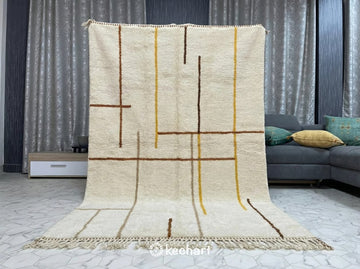 Close-up view of the thick, hand-knotted wool pile and traditional fringe of a bespoke Moroccan rug showing the rich Sierra and saffron color variations.