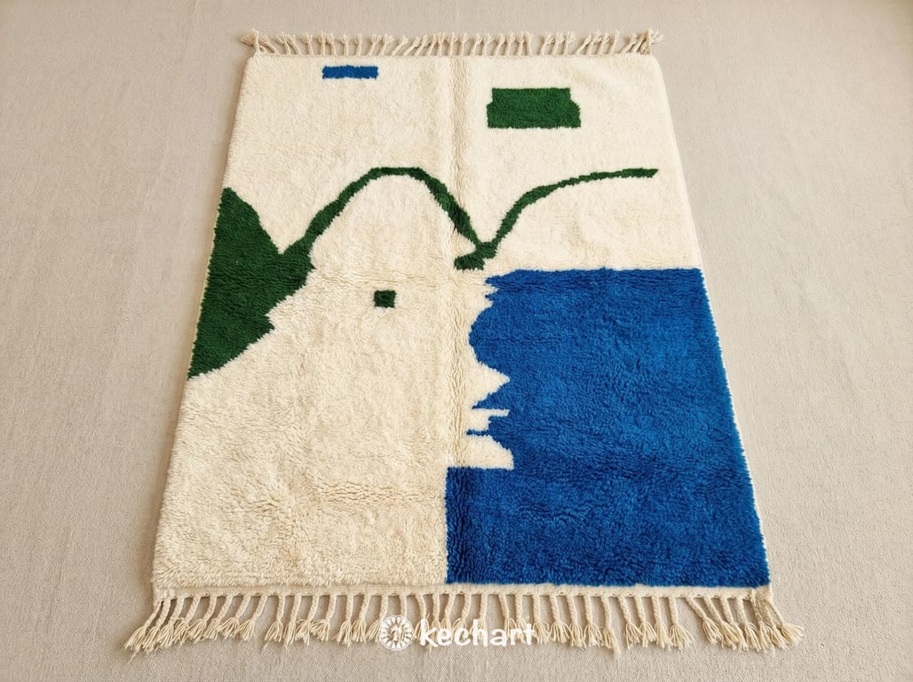 Custom made Beni Ourain rug flat lay showing plush soft white wool texture with Moroccan blue and fir green geometric diamond patterns and traditional fringe.